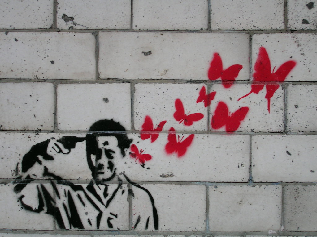 Графити. Человек стреляет себе в голову, вылетают красные бабочки.